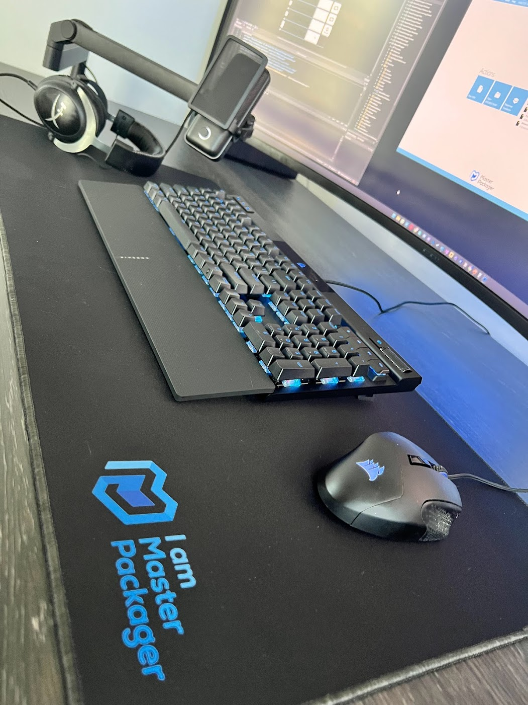 Gaming mouse pad, designed with space for a keyboard, mouse, mobile, and headphones, featuring the Master Packager logo.